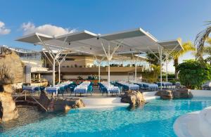 a resort with a pool with tables and chairs at Adrián Hoteles Jardines de Nivaria in Adeje