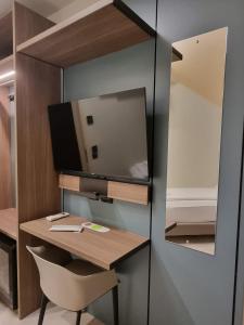a desk with a mirror and a television on a wall at Hotel HDomus in Nogarole Rocca