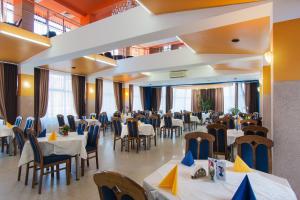 uma sala de jantar com mesas e cadeiras num restaurante em Motel Blue River Calimanesti em Călimăneşti