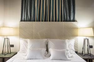 a bedroom with a bed with white pillows and two lamps at Hotel Villa Linneo in Rome