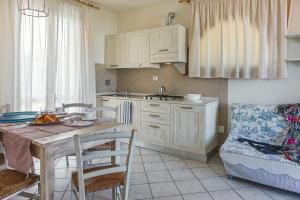 a kitchen with white cabinets and a table and a couch at Villetta Tina in Vada