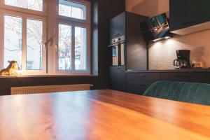 a kitchen with a wooden table and two windows at Cityloft Erfurt in Erfurt
