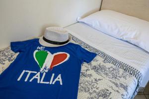 a blue t shirt with a hat sitting on a bed at Villetta Tina in Vada