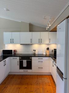 a kitchen with white cabinets and a wooden floor at Semesterhus nära Köpingsvik in Köpingsvik