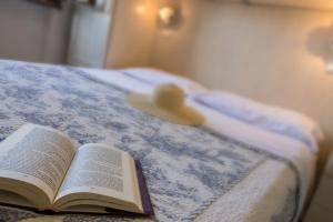 a book on a bed with a hat on it at Villetta Tina in Vada