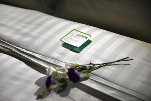 a white pillow with purple flowers on a bed at City Place Hotel in Tainan