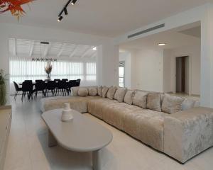 a living room with a large couch and a table at וילה ג'נסיס - וילה מהממת למשפחות עם בריכה פרטית מחוממת ליד הכנרת in Migdal +14 photos