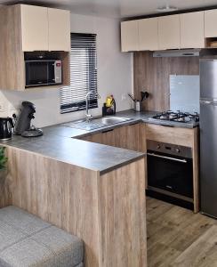 a kitchen with wooden cabinets and a stainless steel refrigerator at Chalet Lauwersoog mét airco! in Lauwersoog +14 photos