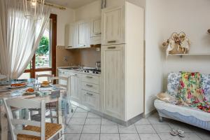 a kitchen with white cabinets and a table and a dining room at Villetta Tina in Vada