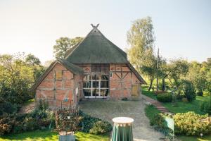 a barn with a thatched roof in a garden at Alter Hof am Elbdeich in Unbesandten