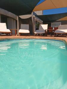 a large swimming pool with chairs and a table at Clanwilliam Waterside Villa in Clanwilliam