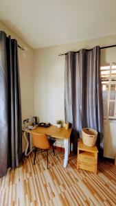 a room with a desk and a table and curtains at Esther & Hans Homes in Dodoma