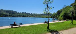 two people sitting on benches in a park near a lake at Maison familiale in Bidart