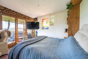 a bedroom with a bed and a tv and a balcony at Cosy rustic cabin with hot tub and country views in Llanelli