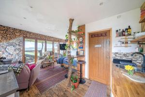a kitchen and living room with a tree in the middle at Cosy rustic cabin with hot tub and country views in Llanelli