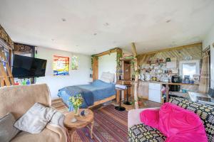 a living room with a bed and a couch at Cosy rustic cabin with hot tub and country views in Llanelli
