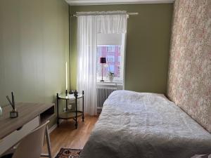a bedroom with a bed and a desk and a window at Farsta Bed and Breakfast in Stockholm
