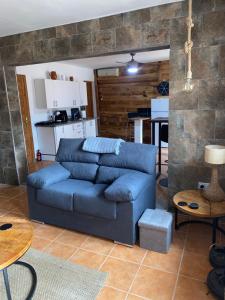 a living room with a blue couch and a kitchen at Casa Amigos Rural in Cuevas del Almanzora