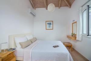 a white bedroom with a white bed and a window at Schiza Houses in Finikounta