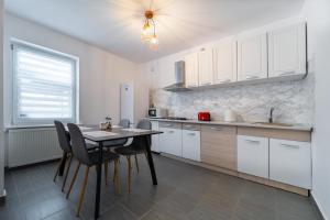 a kitchen with white cabinets and a table and chairs at Vila Petro in Iaşi