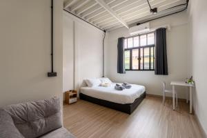 a bedroom with a bed and a couch and a window at Cool cozy In Yaowarat in Bangkok