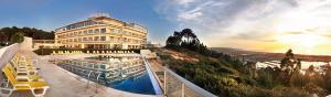 een gebouw met een zwembad en ligstoelen bij Hotel Miramar Sul in Nazaré