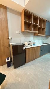 a kitchen with a black refrigerator and wooden cabinets at Sorici Studio at Bella Tower in Surabaya