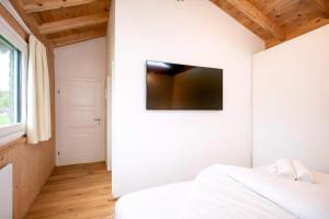 a bedroom with a white wall with a flat screen tv at Tyrolschalet LITTLE LUCK - Private Pool & Mountain View in Rofansiedlung +13 photos