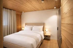 a bedroom with a large white bed with wooden ceilings at RACING Suite - Terrace & Sauna Access in Kleinboden