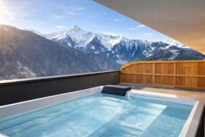 a hot tub with a view of the mountains at SKYLINE Chalet - Two-Level Penthouse with Private Whirlpool in Mühlen +28 photos