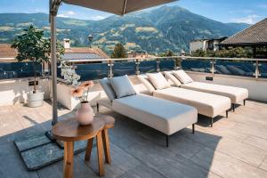 a patio with white couches and a table and mountains at CLOUD 9 - Private Whirlpool & Rooftop Terrace in Fügen