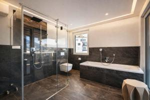 a bathroom with a tub and a shower and a sink at CLOUD 9 - Private Whirlpool & Rooftop Terrace in Fügen