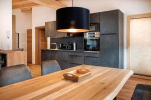 a kitchen with a wooden table and a black wall at ViVaZILARE - Design Loft with Terrace in Fügen