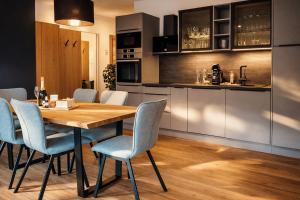 a kitchen and dining room with a wooden table and chairs at RUHESTUBE - Design Apartment with Balcony in Fügen