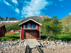 a red house with a mountain in the background at Unique boathouse with a spectacular view in Oldra