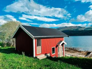 a red building next to a body of water at Unique boathouse with a spectacular view in Oldra