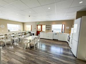 a dining room with tables and chairs and a refrigerator at Við Hafið Oceanfront Guesthouse in Ólafsvík