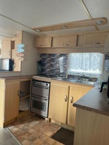 a kitchen with wooden cabinets and a stove top oven at Coastal Getaway, camber sands in Camber