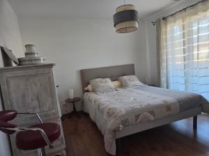 a bedroom with a bed and a chair and a window at Chez Titelle in Saint-Laurent-de-la-Salanque
