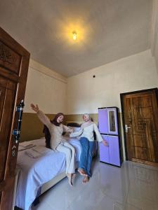 two women sitting on a bed in a room at Cemara Paradise Homestay in Pulau Gilimelayu