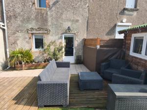 a patio with wicker furniture on a wooden deck at Le repos beaurepairien in Beaurepaire +3 photos
