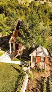 a small log cabin with a porch and a tree at Guest House Ledio in Valbonë