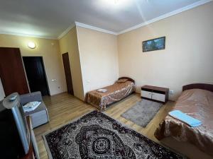 a small room with two beds and a rug at Hotel Nurlytau in Borovoye