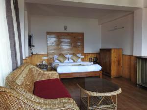 a bedroom with a bed and a couch and a table at Hotel Kabur in Pelling