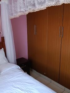 a bedroom with a bed and some wooden cabinets at Greatwall golden stay in Machakos