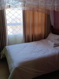 a bedroom with a white bed with a window at Greatwall golden stay in Machakos