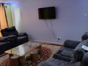 a living room with two couches and a tv on the wall at Greatwall golden stay in Machakos