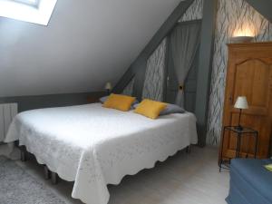a bedroom with a white bed with yellow pillows at chambre d'hôte équipée en studio in Molliens-Vidame