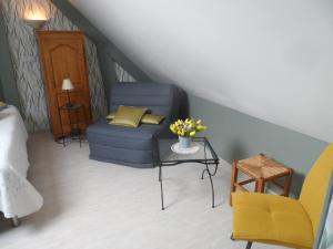 a living room with a blue chair and a couch at chambre d'hôte équipée en studio in Molliens-Vidame