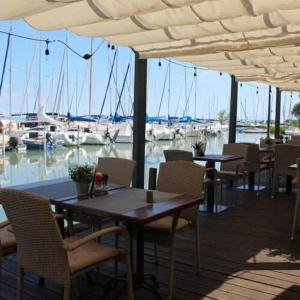a restaurant with tables and chairs and a marina with boats at Siófok Panoráma Apartman in Siófok